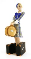 Lot 80 - A Goldscheider figure of a woman holding a hat box, holding two suitcases