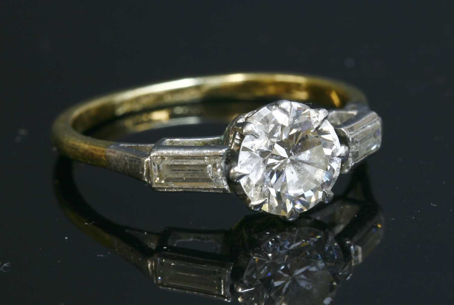 Lot 175 - A single stone diamond ring with baguette cut diamonds shoulders