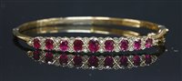 Lot 384 - A 9ct gold ruby and diamond hinged bangle