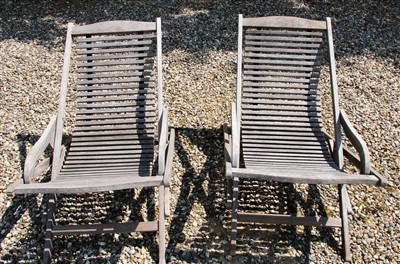 Lot 497 - A pair of teak rocking garden loungers