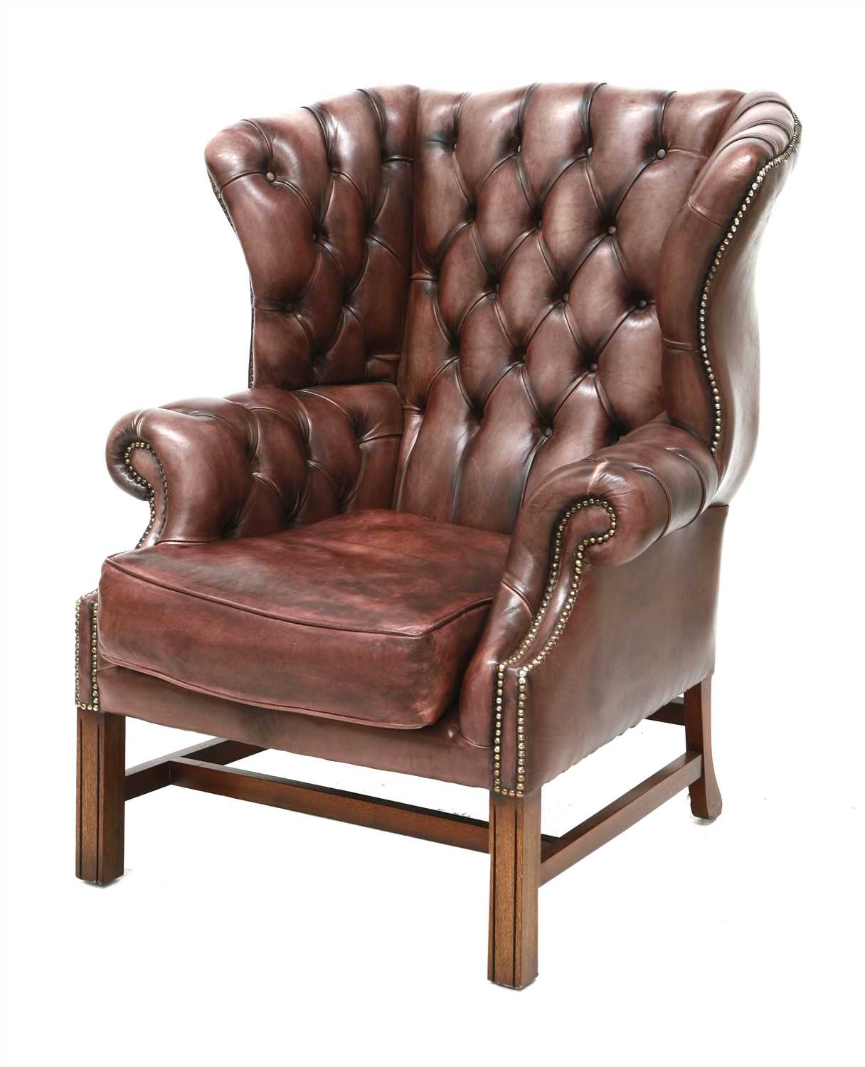 Lot 129 - A deep buttoned brown leather wing armchair