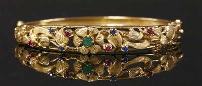 Lot 287 - A 9ct gold emerald, ruby and sapphire set hinged bangle, c.1970