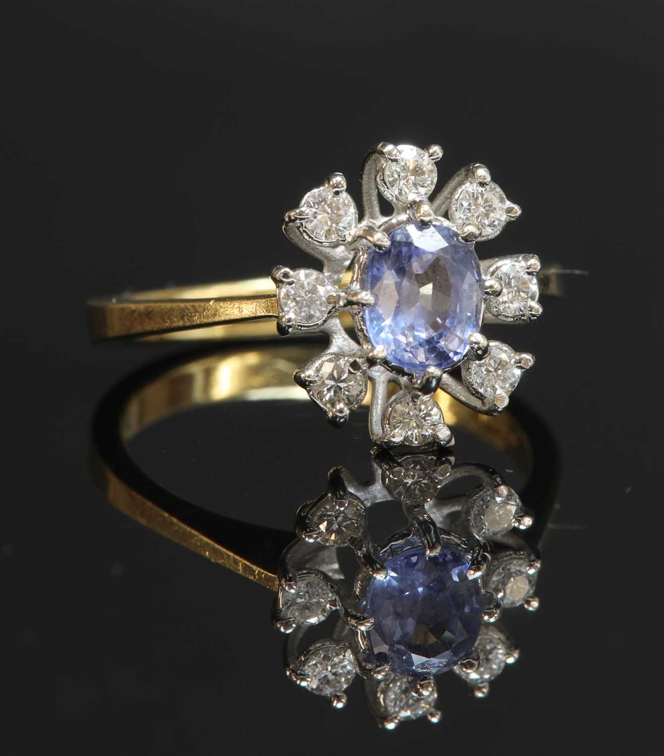 Lot 333 - An 18ct gold sapphire and diamond dispersed oval cluster ring