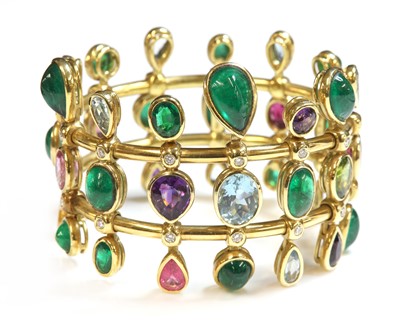 Lot 294 - An 18ct gold emerald, aquamarine, amethyst, tourmaline, peridot and diamond hinged bangle