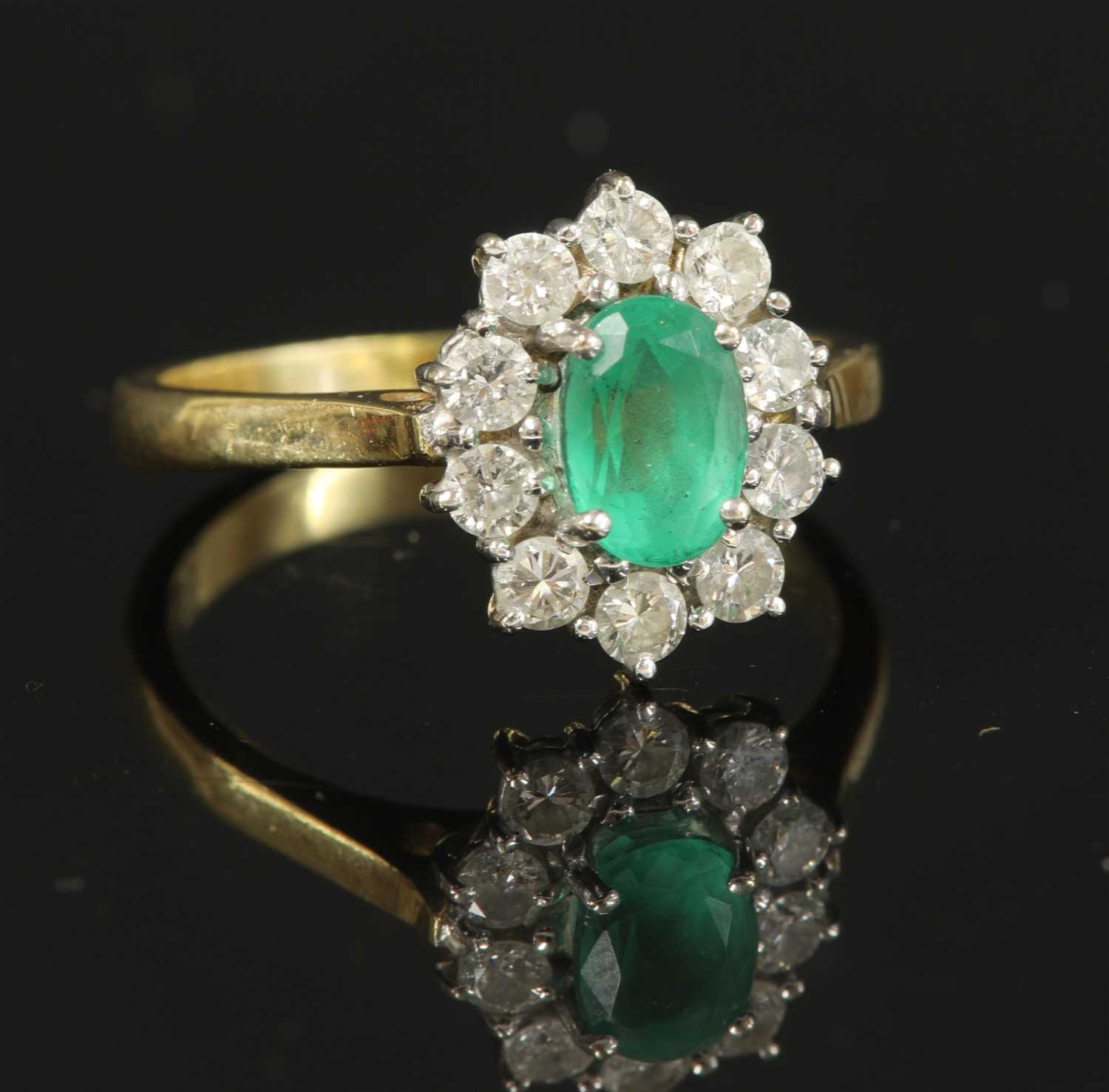 Lot 340 - An 18ct gold emerald and diamond oval cluster ring