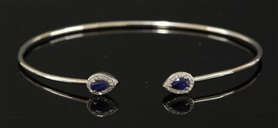 Lot 519 - A white gold sapphire and diamond torque bangle