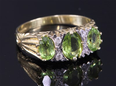 Lot 339 - An 18ct gold three stone graduated peridot carved head style ring