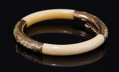 Lot 215 - An early 20th century Chinese carved ivory and gold-mounted hinged bangle