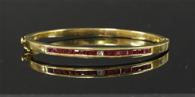 Lot 91 - A gold diamond and ruby set flat section hinged bangle