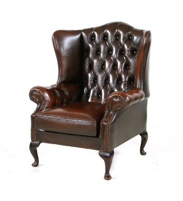 Lot 696 - A brown buttoned leather wing armchair