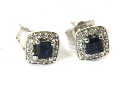 Lot 1057 - A pair of white gold sapphire and diamond cluster earrings