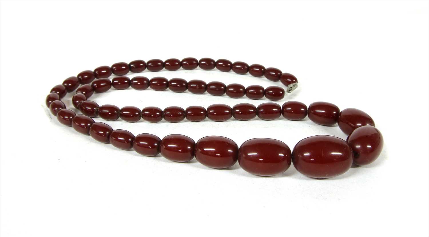 Lot 69 - A single row graduated cherry coloured olive shaped Bakelite bead necklace