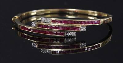 Lot 193 - A gold ruby and diamond crossover hinged bangle