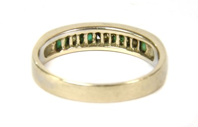 Lot 116 - A white gold diamond and emerald half eternity ring