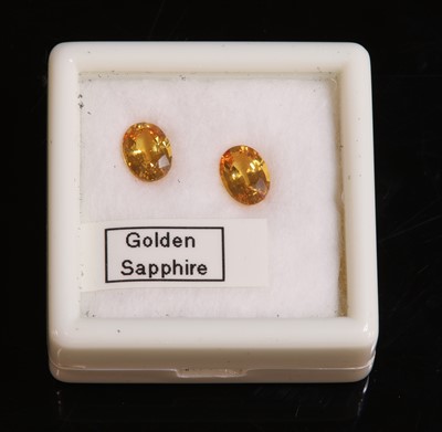 Lot 320 - A pair of oval mixed cut golden yellow sapphires