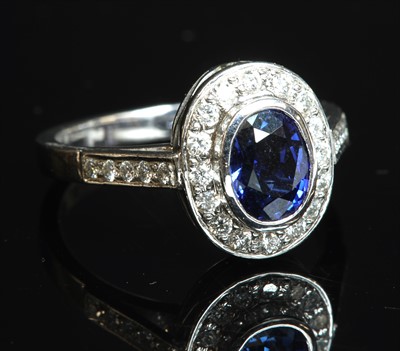Lot 228 - An 18ct white gold sapphire and diamond oval cluster ring