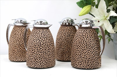 Lot 1208 - Four animal print covered hot water jugs