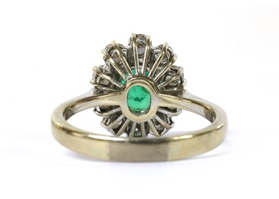 Lot 1187 - An 18ct white gold emerald and diamond oval cluster ring
