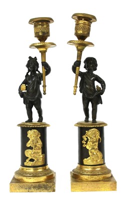Lot 130 - A pair of bronze parcel-gilt figural candlesticks