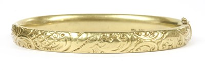 Lot 101 - A gold hollow hinged oval bangle