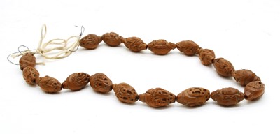 Lot 239 - A Chinese necklace of eighteen carved nut beads