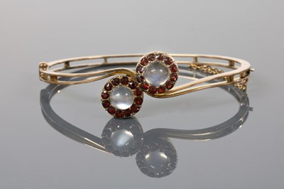 Lot 84 - A gold moonstone and garnet cluster crossover bangle