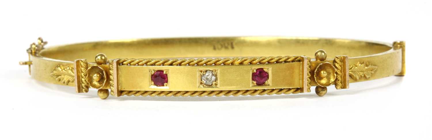 Lot 34 - A gold diamond and ruby set oval hinged bangle