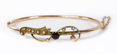 Lot 53 - A hollow gold garnet and split pearl bangle