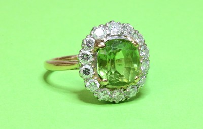 Lot 140 - A two colour gold peridot and diamond oval cluster ring