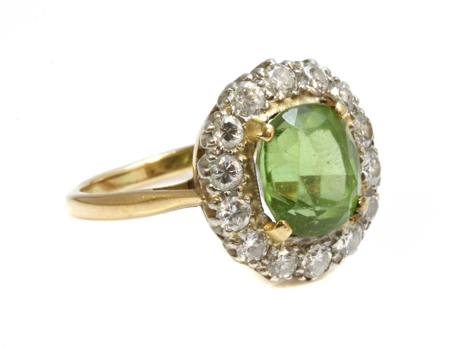 Lot 140 - A two colour gold peridot and diamond oval cluster ring
