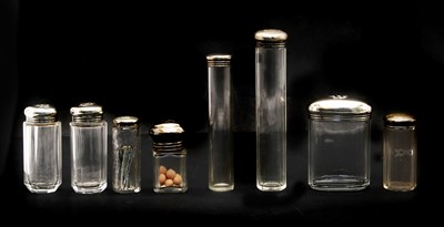 Lot 43 - A collection of silver lidded glass scent and drawing table jars