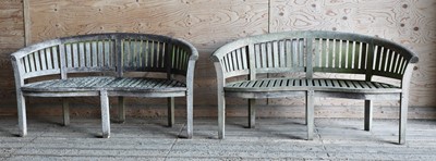 Lot 981 - A pair of Lutyens-style curved teak garden benches