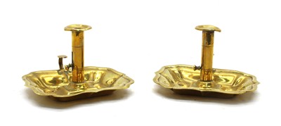 Lot 86 - An early pair of brass chambersticks having scalloped rims