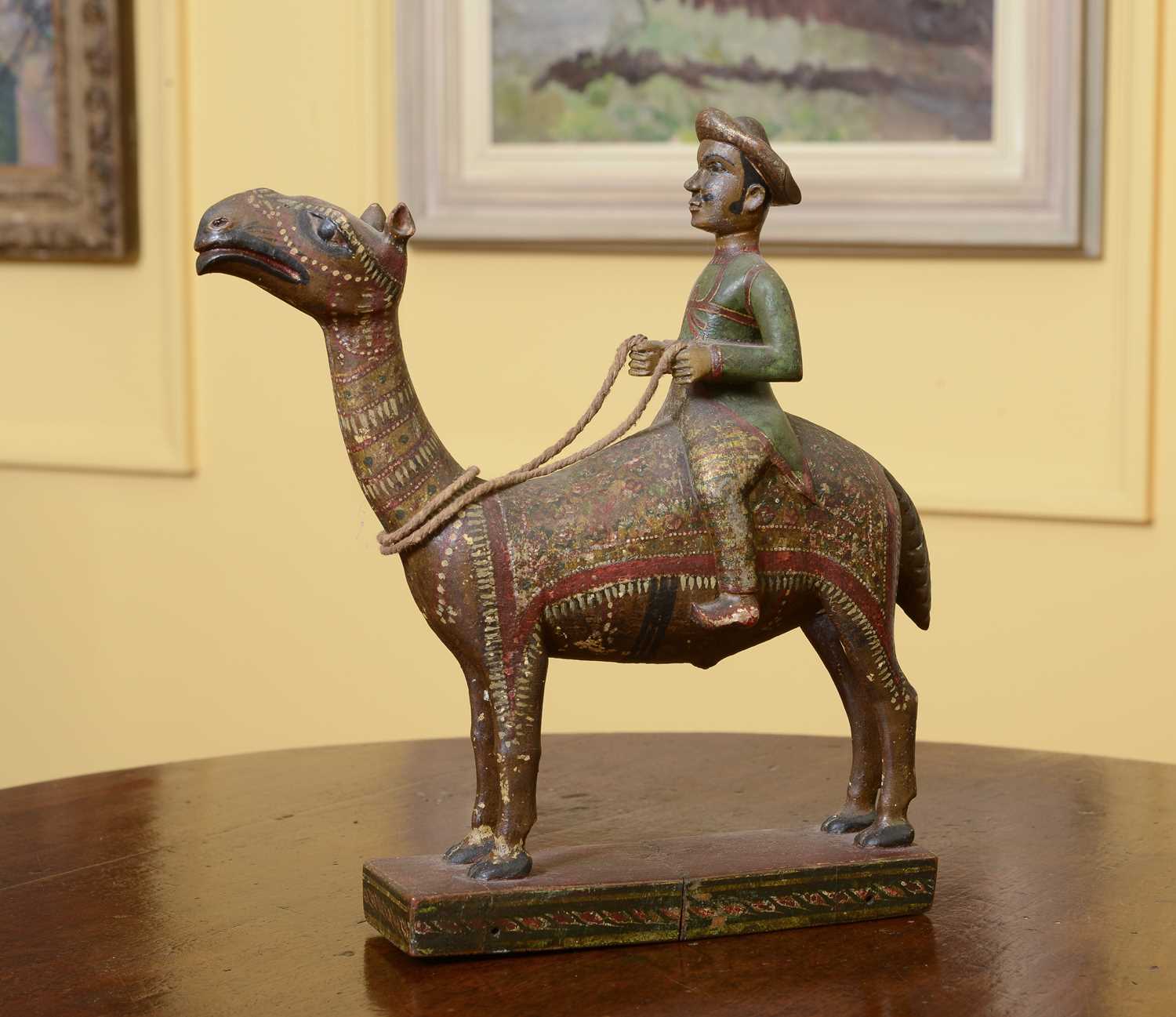 Lot 104 - A carved wooden and polychromed figure of a gentleman riding a camel