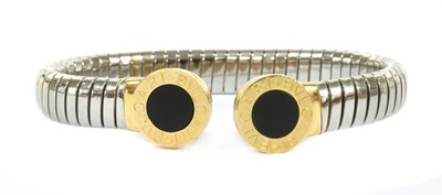 Lot 180 - A steel, gold and onyx tubogas torque bangle by Bulgari