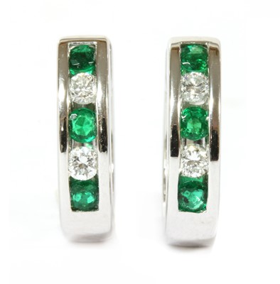 Lot 151 - A pair of 18ct white gold emerald and diamond oval hoop earrings