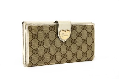 Lot 101 - A Gucci beige monogrammed canvas and cream leather heart bi-fold wallet