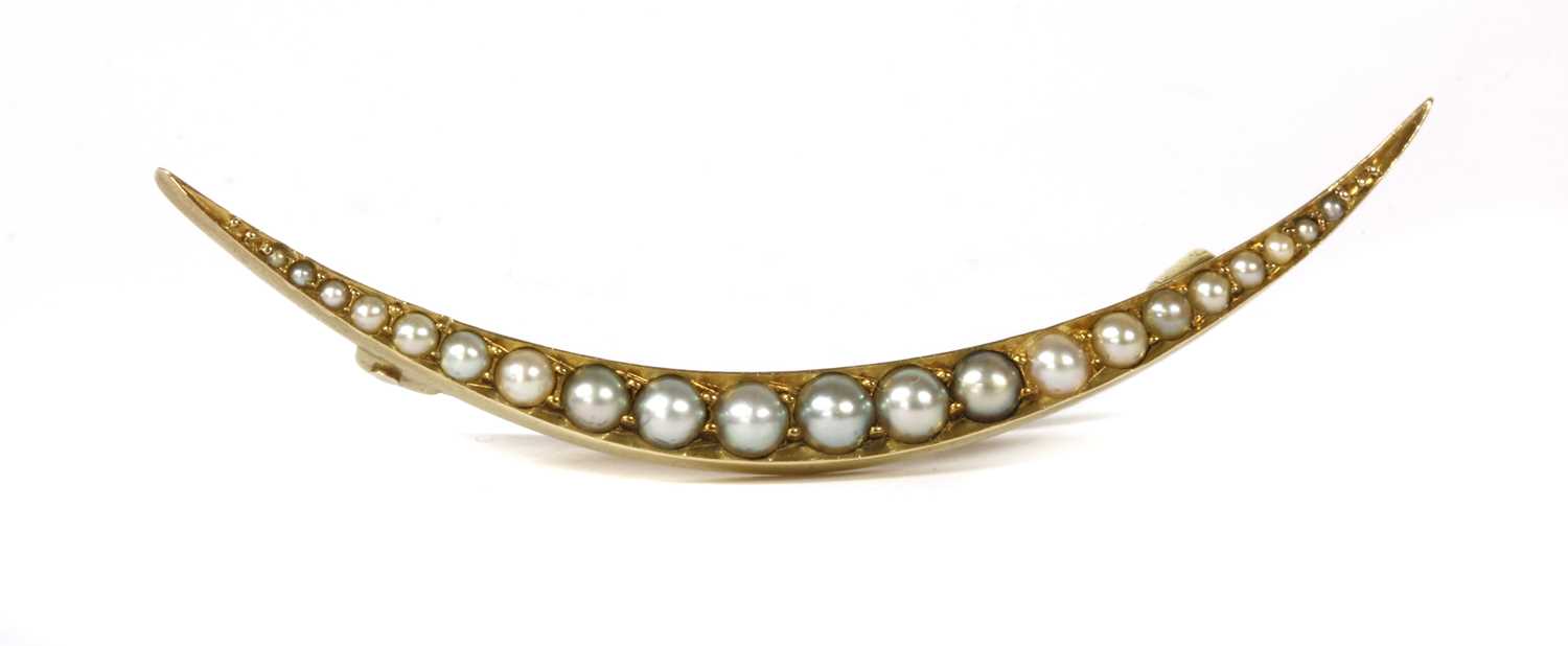 Lot 26 - An Edwardian gold split pearl open crescent brooch