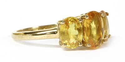 Lot 231 - A gold three stone yellow sapphire ring
