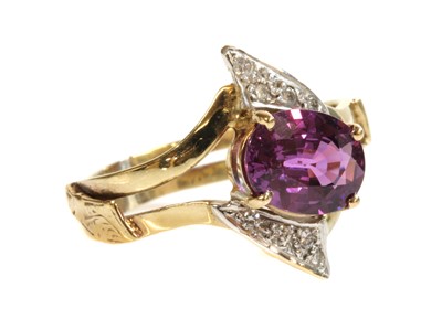 Lot 427 - A gold single stone pink sapphire and diamond crossover ring