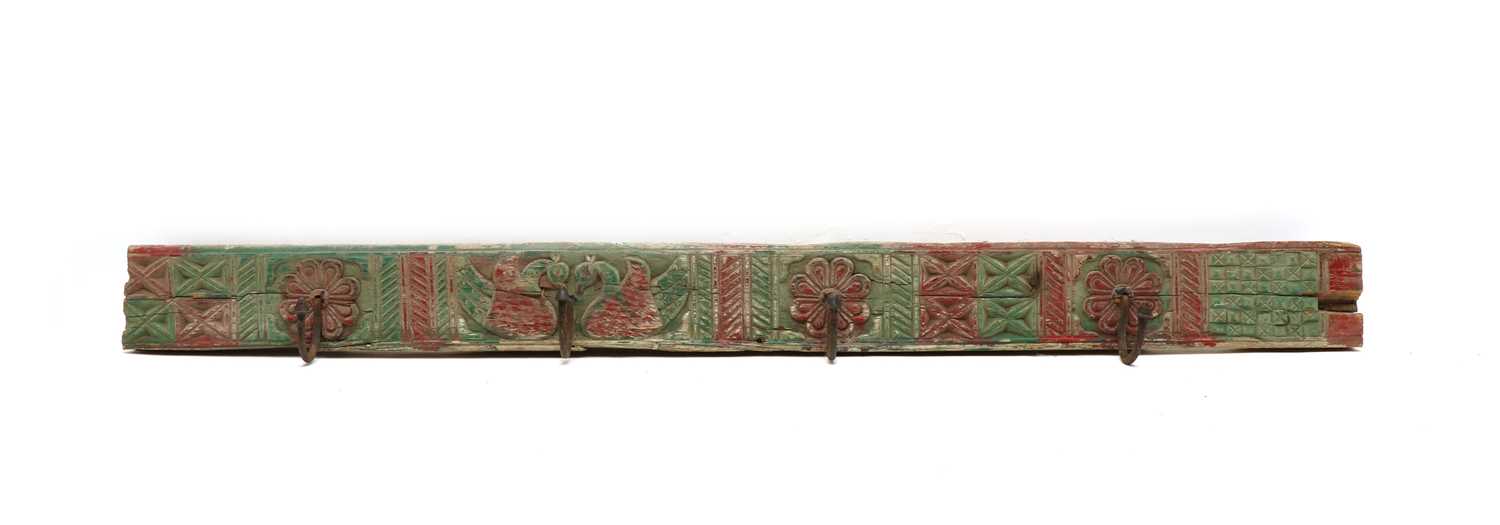 Lot 193 - An Indian carved wood and polychrome decorated rack of four coat hooks