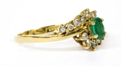 Lot 112 - An 18ct gold emerald and diamond crossover cluster ring