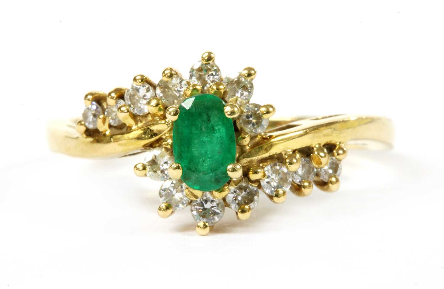 Lot 112 - An 18ct gold emerald and diamond crossover cluster ring