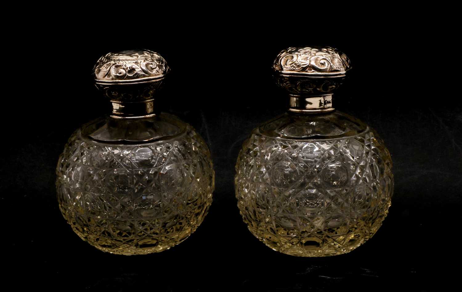 Lot 37 - A pair of globular cut glass silver topped scent bottles