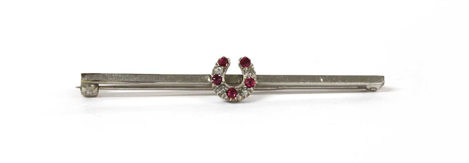 Lot 7 - A white gold ruby and diamond horseshoe bar brooch
