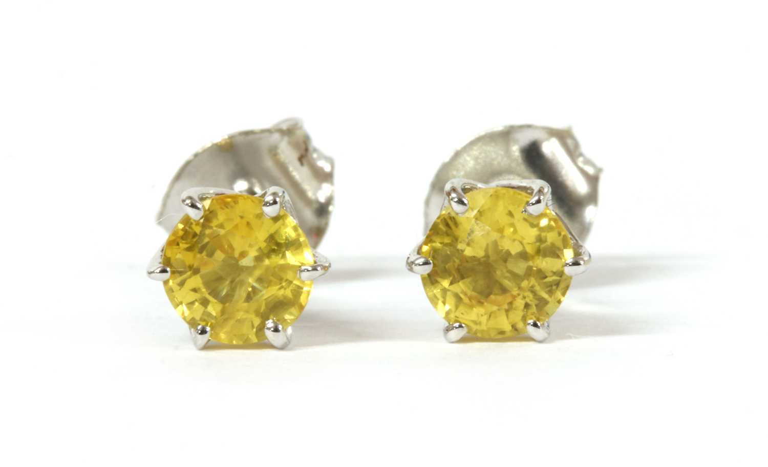 Lot 182 - A pair of white gold single stone yellow sapphire stud earrings