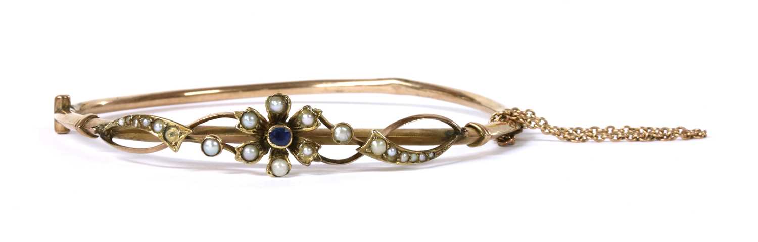 Lot 1025 - An Edwardian gold sapphire and split pearl bangle