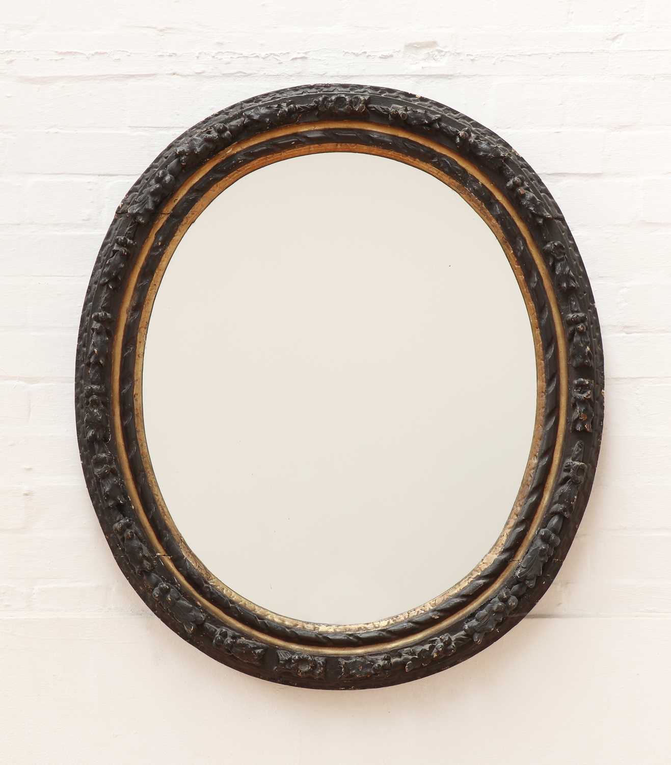 Lot 516 - A carved giltwood and ebonised oval wall mirror