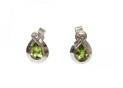 Lot 1263 - A pair of 18ct white gold peridot and diamond stud earrings