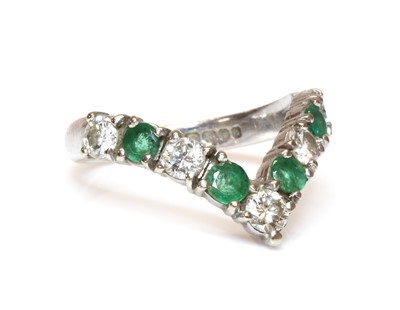 Lot 351 - An 18ct white gold diamond and emerald half wishbone ring